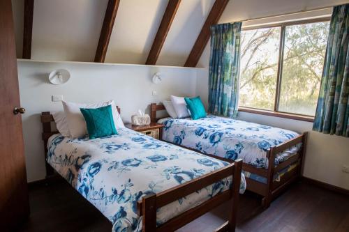 1 dormitorio con 2 camas y ventana en Caves Road Chalets, en Margaret River Town