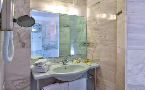 a white bathroom with a sink and a mirror at Spilia Village Hotel & Villas in Spiliá