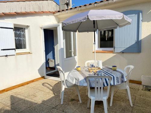 une table et des chaises avec un parasol sur une terrasse dans l'établissement Maison de Vacances Cosy à 800m de la Plage avec Cour Privative et Accès WIFI - FR-1-231-161, à Bretignolles-sur-Mer