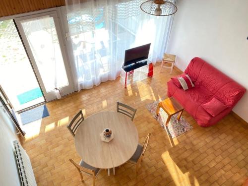 un salon avec une table et un canapé rouge dans l'établissement Maison Tout Confort avec Mezzanine à 300m de la Plage - Wifi, Terrasse, Parking Privé - FR-1-231-246, à Bretignolles-sur-Mer