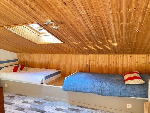 deux lits dans une chambre avec un plafond en bois dans l'établissement Maison Tout Confort avec Mezzanine à 300m de la Plage - Wifi, Terrasse, Parking Privé - FR-1-231-246, à Bretignolles-sur-Mer