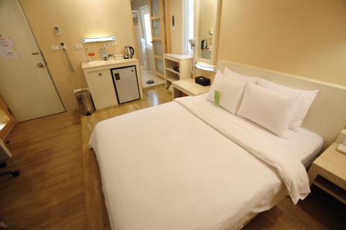 a bedroom with a large white bed and a bathroom at Kindness Hotel - Hanshen in Kaohsiung