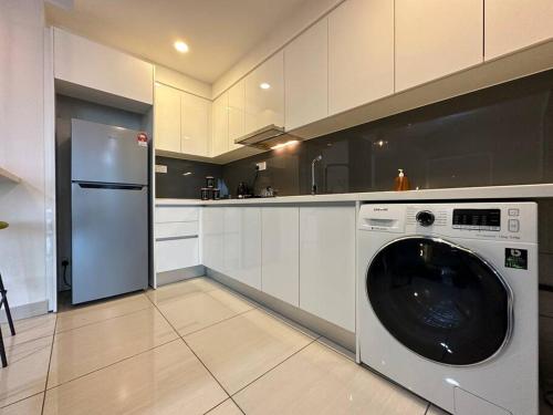 eine Küche mit einer Waschmaschine und einem Kühlschrank in der Unterkunft Almas suites Cozy NETFLIX100mbps By STAY in Nusajaya