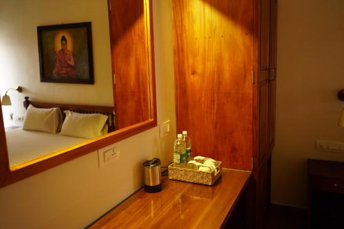 un bagno con specchio e un letto in una camera di Buddha Beach Hotel a Kovalam