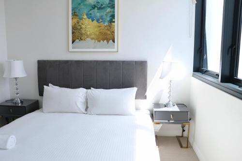 ブリスベンにあるKooii Apartmentsの白いベッドと壁に絵画が飾られたベッドルーム1室