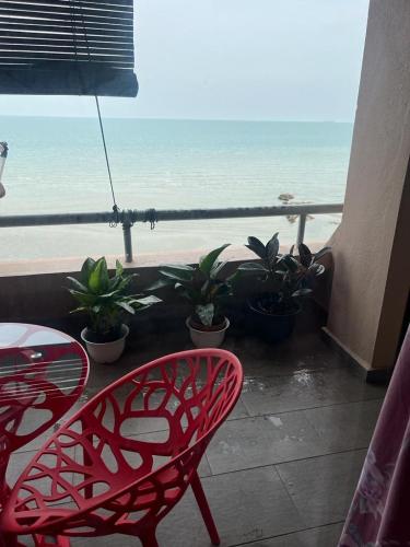 a red chair sitting on a balcony with a view of the beach at PD VIP SEAVIEW w Wifi n Smart TV in Port Dickson
