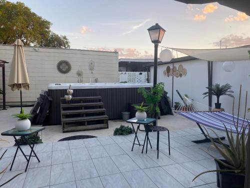 un patio con mesas y sillas y una bañera de hidromasaje. en Tiny place w private hot jacuzzi 7 min to Miami international airport en Miami
