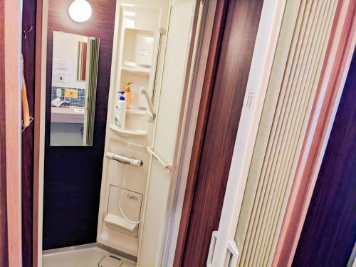 a small bathroom with a refrigerator in a room at Hostel JIN in Osaka