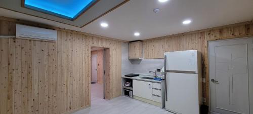 Una cocina con paredes de madera y un refrigerador blanco. en RG Pension, en Hadong