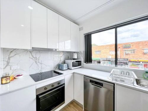 a kitchen with white appliances and a large window at Brand new 2 Bedrooms Apartment in Ingleburn in Ingleburn