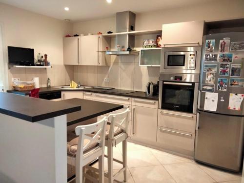 une cuisine avec des appareils en acier inoxydable et des armoires blanches dans l'établissement Maison cosy à La Chaume, jardin, véranda, 3 chambres, proche quais et piscines - FR-1-331-221, à Les Sables-dʼOlonne