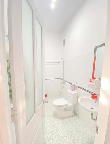 a white bathroom with a toilet and a sink at O Vững's Homestay in Vung Tau