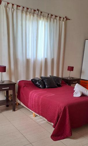 a bedroom with a bed with red sheets and a window at La Ñata in Chicoana