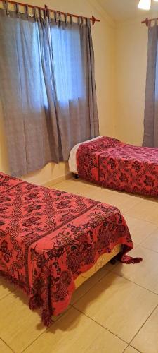 a room with two beds with red covers and a window at La Ñata in Chicoana