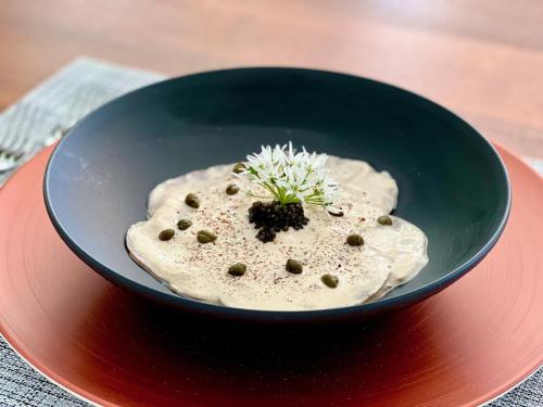 a black bowl of food on a red plate at perfect lifestyle Design Boutique & Private SPA in Gebenstorf