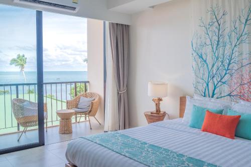 a bedroom with a bed and a balcony with the ocean at Bandara Beach Resort, Phuket in Panwa Beach