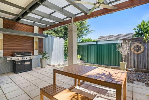 a patio with a wooden table and a grill at Goodie Goodwood Family Home in Unley