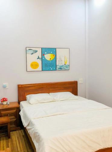 a bed in a bedroom with three pictures on the wall at Sohi Homestay in Quy Nhon