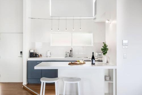 a white kitchen with a blue and white counter and stools at The Sail House at Seacliff in Seacliff