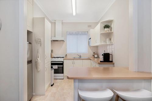 a kitchen with white cabinets and a wooden counter top at Broadway Getaway - 150 Metres to Beach in Glenelg
