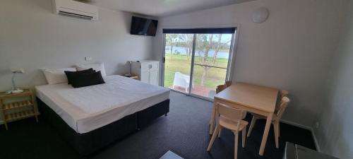 Schlafzimmer mit einem Bett, einem Tisch und einem Fenster in der Unterkunft Narangba Motel (formerly Brisbane North B&B and Winery) in Narangba