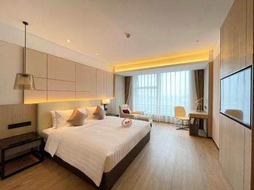 a hotel room with a large bed and a desk at Kew Green Hotel Hongqiao Shanghai in Shanghai