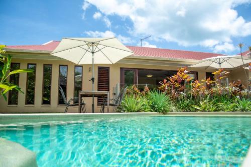 a house with a swimming pool in front of a house at Belle Escapes Villa Latania Palm Cove in Palm Cove