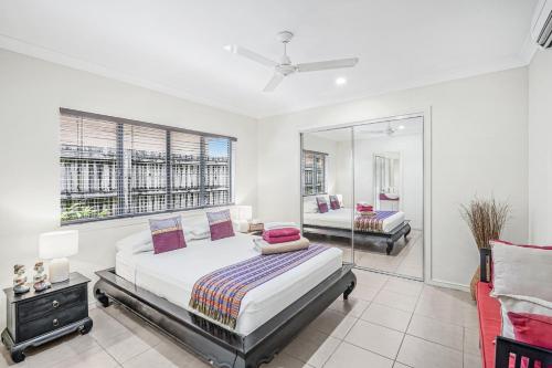 a bedroom with a large bed and a mirror at Belle Escapes Villa Latania Palm Cove in Palm Cove