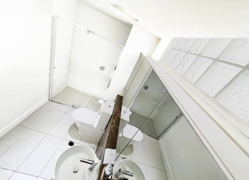 a bathroom with a toilet and a glass staircase at Oshen Holiday Apartments Yeppoon in Yeppoon