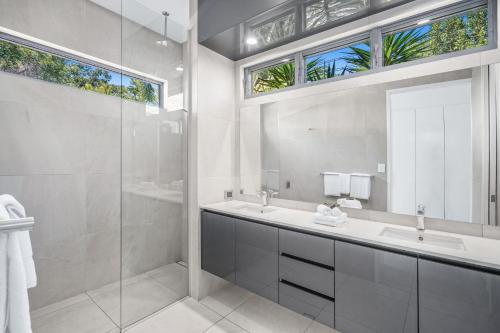 a bathroom with a shower and a sink and a mirror at Belle Escapes Tranquil Waters Luxury Home Palm Cove in Palm Cove