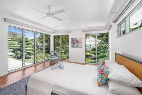 sypialnia z łóżkiem i dużymi oknami w obiekcie Belle Escapes Tranquil Waters Luxury Home Palm Cove w mieście Palm Cove