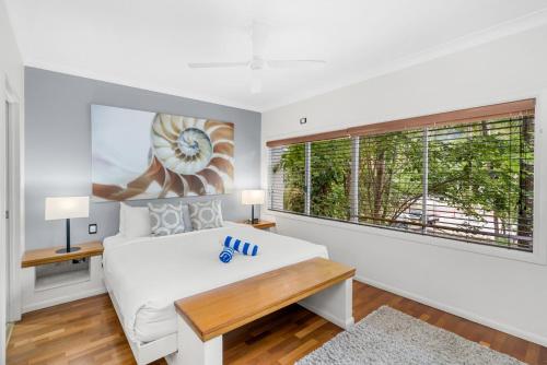 a white bedroom with a large bed and a window at Belle Escapes Poolview Suite 74 Alamanda Resort Palm Cove in Palm Cove