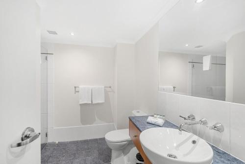 a white bathroom with a toilet and a sink at Belle Escapes Poolview Suite 74 Alamanda Resort Palm Cove in Palm Cove