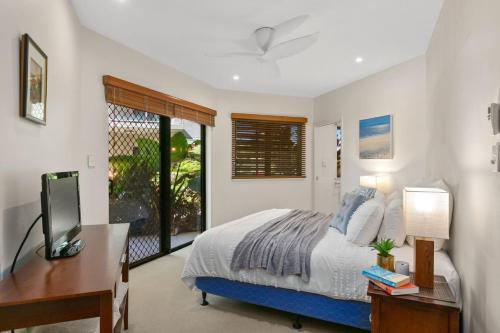 Dormitorio con cama, escritorio y TV en Belle Escapes Ground Floor Beachfront Apartment, en Yorkeys Knob