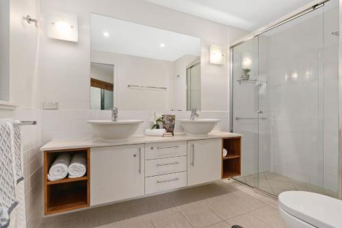 - Baño blanco con 2 lavabos y ducha en Belle Escapes Ground Floor Beachfront Apartment, en Yorkeys Knob
