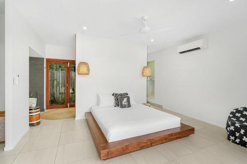 a white bedroom with a bed and a chair at Belle Escapes 94 Cascade Luxury Home Palm Cove in Palm Cove