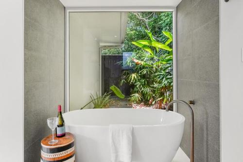 uma banheira na casa de banho com uma janela em Belle Escapes 94 Cascade Luxury Home Palm Cove em Palm Cove