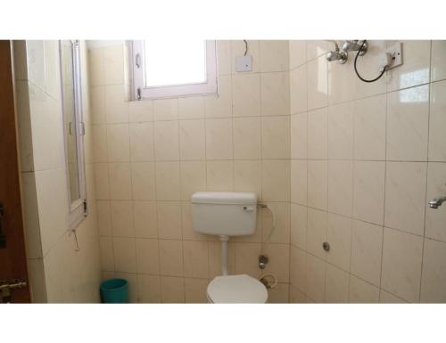 a small bathroom with a toilet and a window at Hotel Kailash, Amritsar in Amritsar