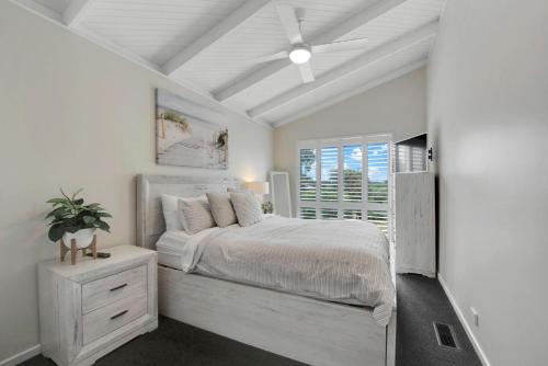 a white bedroom with a bed and a window at Beachside House in Tootgarook