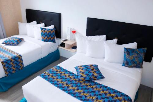 two beds in a hotel room with white and blue pillows at Hotel Alto Mar in Catia La Mar