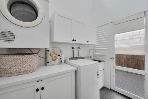 a white kitchen with a sink and a washing machine at Peninsula Retreat in Rye