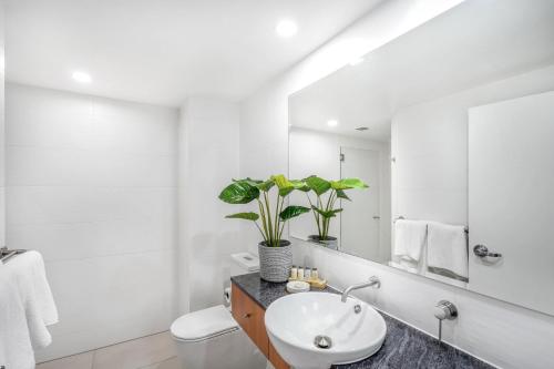 een witte badkamer met een wastafel en een spiegel bij Belle Escapes presents 14 Alamanda Resort Where Pure Luxury meets the Coral Sea in Palm Cove
