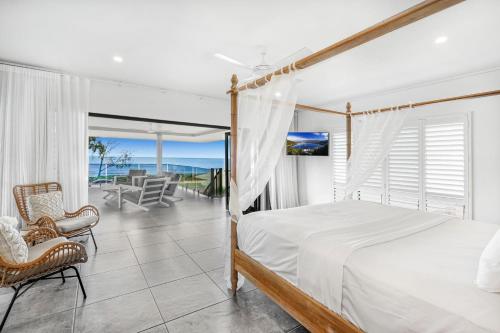 a bedroom with a bed and a balcony with the ocean at Belle Escapes Beachfront Luxury Home 53 Arlington Clifton Beach in Palm Cove