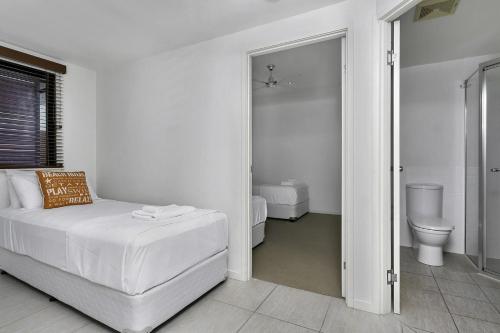ein weißes Schlafzimmer mit einem Bett und einem WC in der Unterkunft Belle Escapes 4 Sims Esplanade Yorkeys Knob in Yorkeys Knob