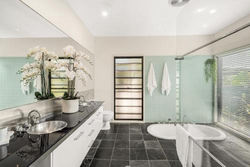 uma casa de banho com 2 lavatórios e uma banheira em Belle Escapes Trinity Blue Oceanview Home em Trinity Beach