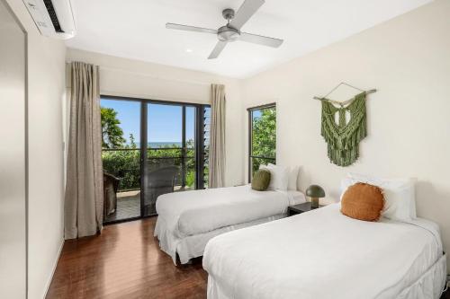 two beds in a room with a window at Belle Escapes Trinity Blue Oceanview Home in Trinity Beach