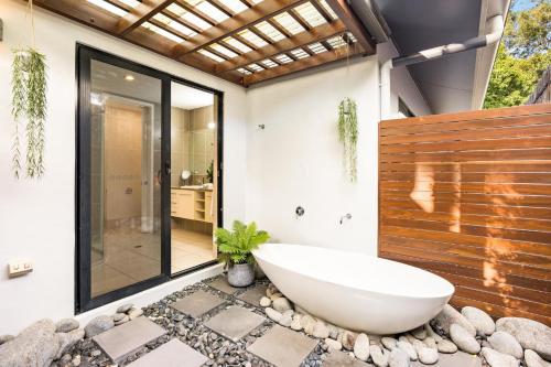 a bathroom with a large tub on rocks at Belle Escapes Watermark Palm Cove Luxury Home in Palm Cove