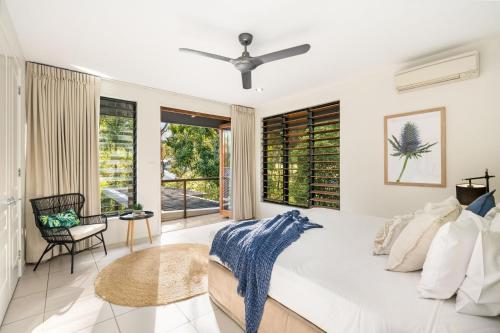 1 dormitorio con 1 cama blanca grande y ventilador de techo en Belle Escapes Watermark Palm Cove Luxury Home, en Palm Cove