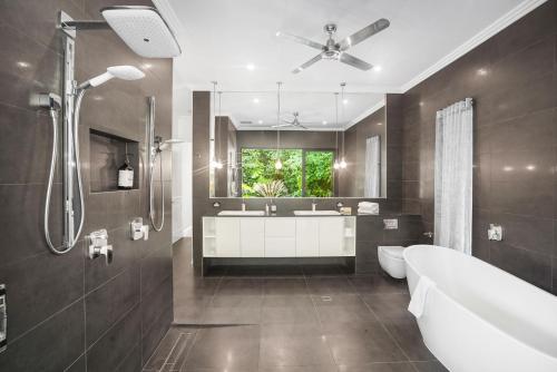 een badkamer met een bad, een wastafel en een douche bij Belle Escapes 58 Ocean Dr Luxury Home Palm Cove in Palm Cove