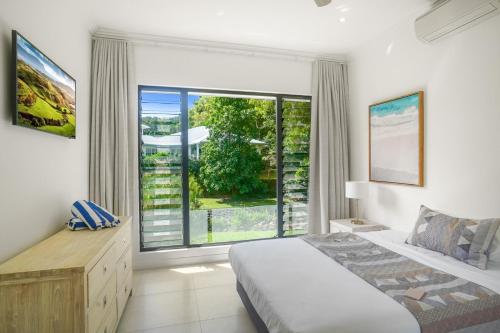 ein Schlafzimmer mit einem Bett und einem großen Fenster in der Unterkunft Belle Escapes 58 Ocean Dr Luxury Home Palm Cove in Palm Cove